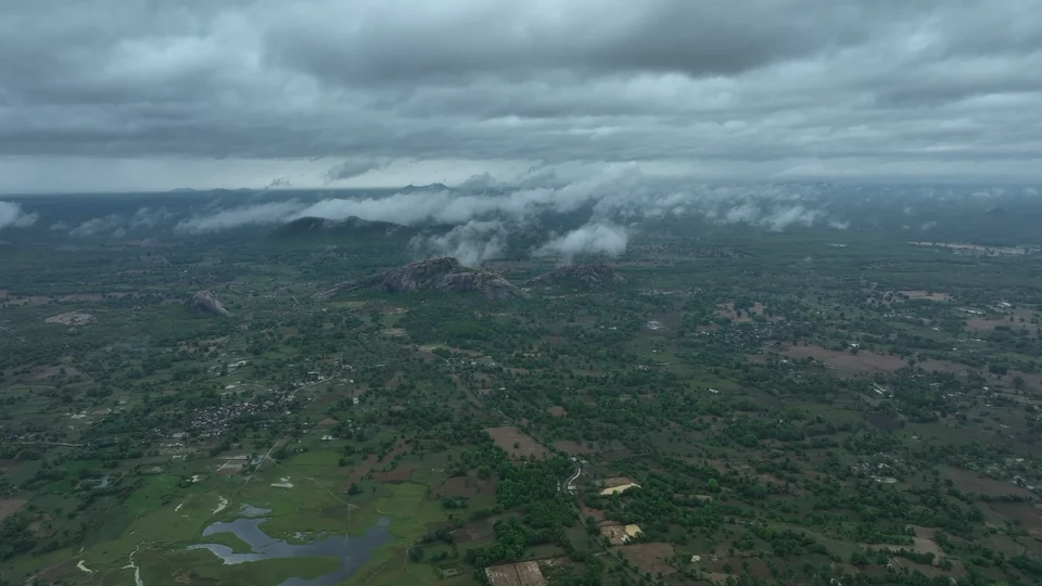 Aerial view of fields, trees and low hills beneath clouds in Odisha