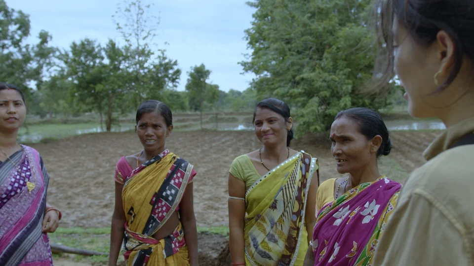 Farmers and visitors talking together beside a field in Odisha